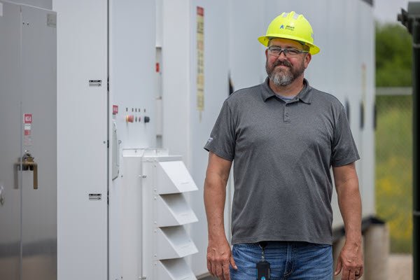 employee standing in front of a battery storage system