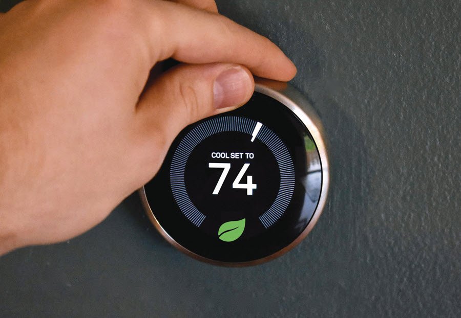 Hand adjusting smart thermostat to 74 degrees Fahrenheit.